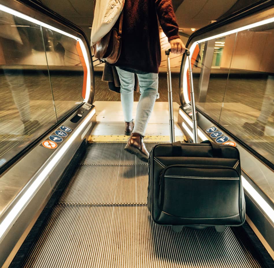 Traveller pulling luggage on escalator at airport