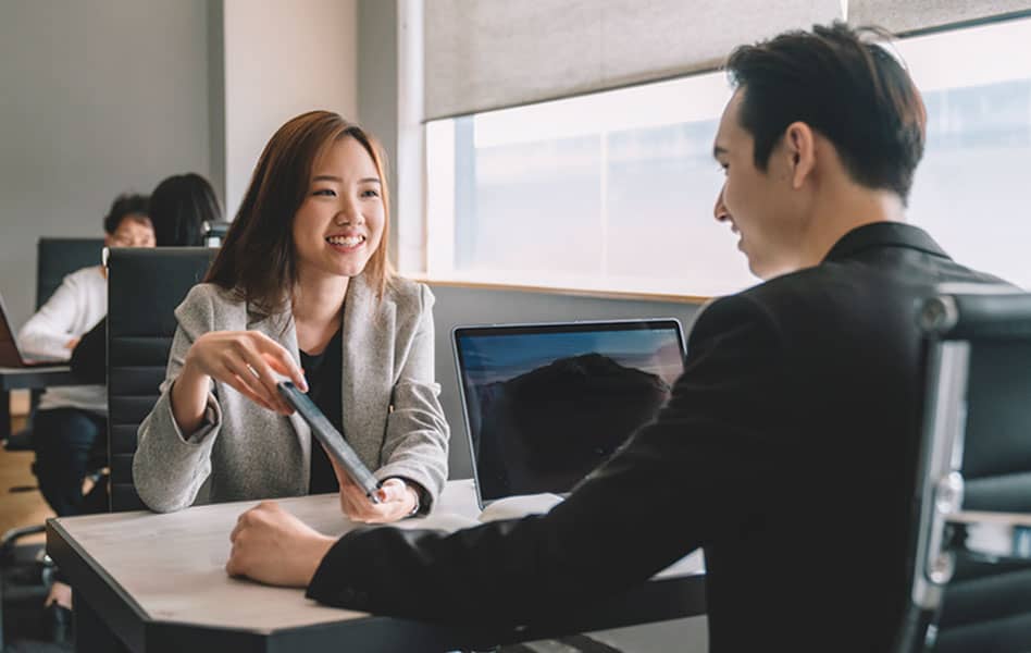 Asian female travel consultant discussing business travel plans with asian businessman in the office